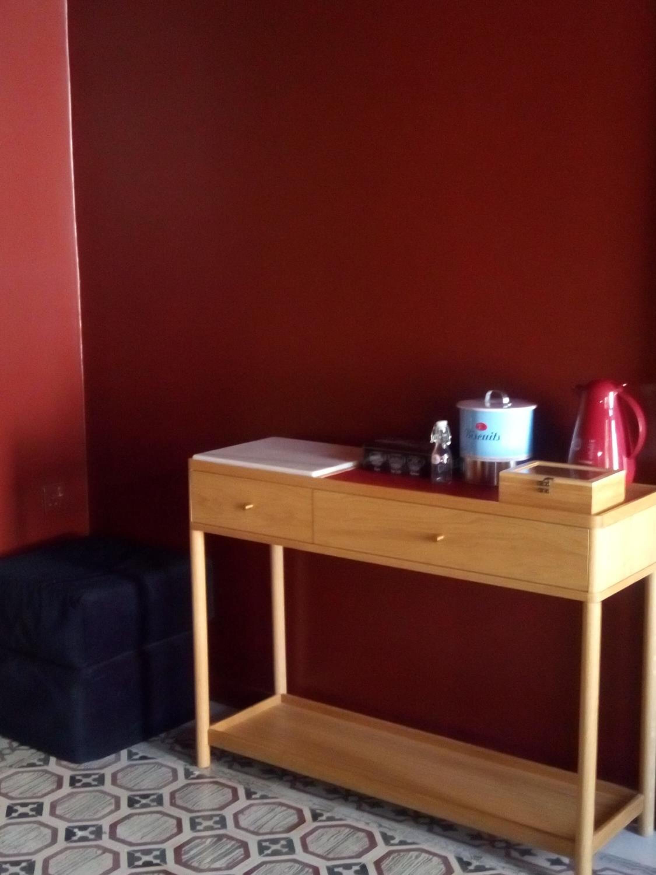 A small wooden desk with a notebook, a thermos, and a kettle.