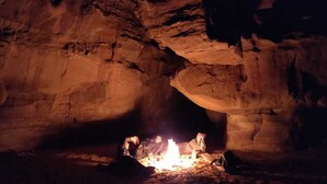 A cave interior with a fire in the center, surrounded by rock formations. - Mars Private camp (Wadi Rum)
