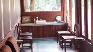 A room with wooden walls, a window with a view of greenery, a sink, and wooden chairs. - Himana Ayurveda (Seeduwa - Katunayake)