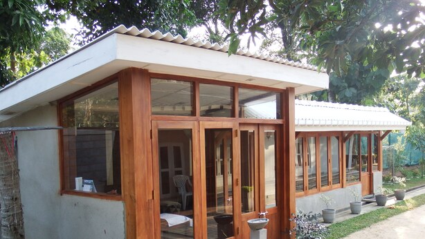 A modern house with large glass doors and windows, a small porch area, and potted plants. - Himana Ayurveda (Seeduwa - Katunayake)