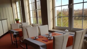 Un comedor con una mesa lista para cuatro personas, ventanas amplias y vistas al exterior.