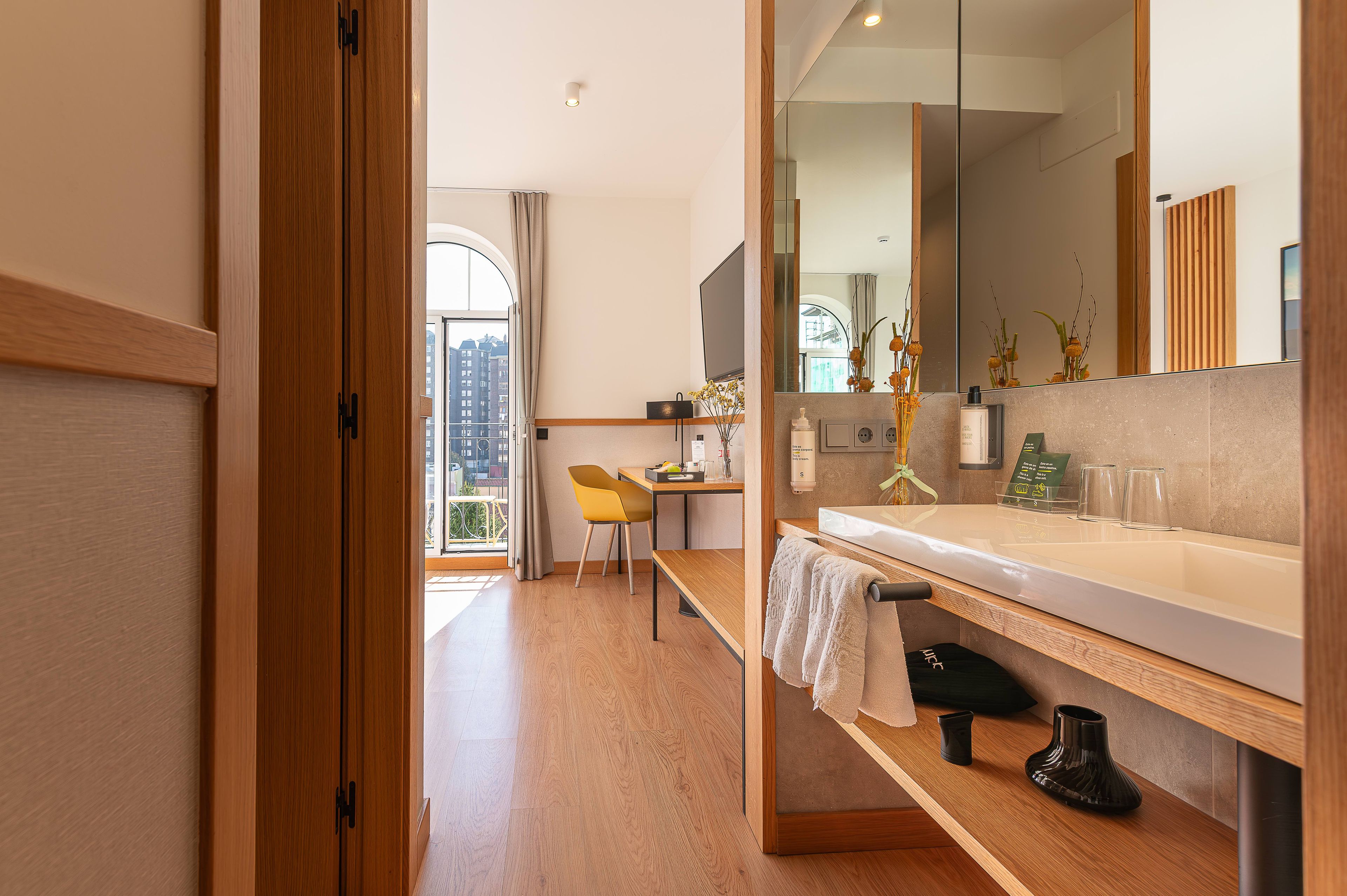 Un bagno moderno con un mobile bagno in legno, uno specchio e vista sulla città.