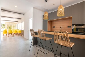 Una cucina moderna con forno integrato, un piano di lavoro in legno e una lampada a sospensione in fibra tessile.