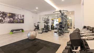 A gym with exercise equipment, a step platform, and a large exercise ball.