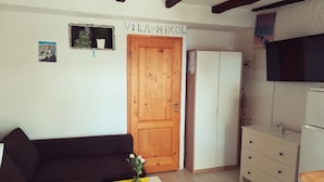 A living room with a wooden door, a white wardrobe, a television, and a small table with a vase. - Studio Rakella (Opatija)