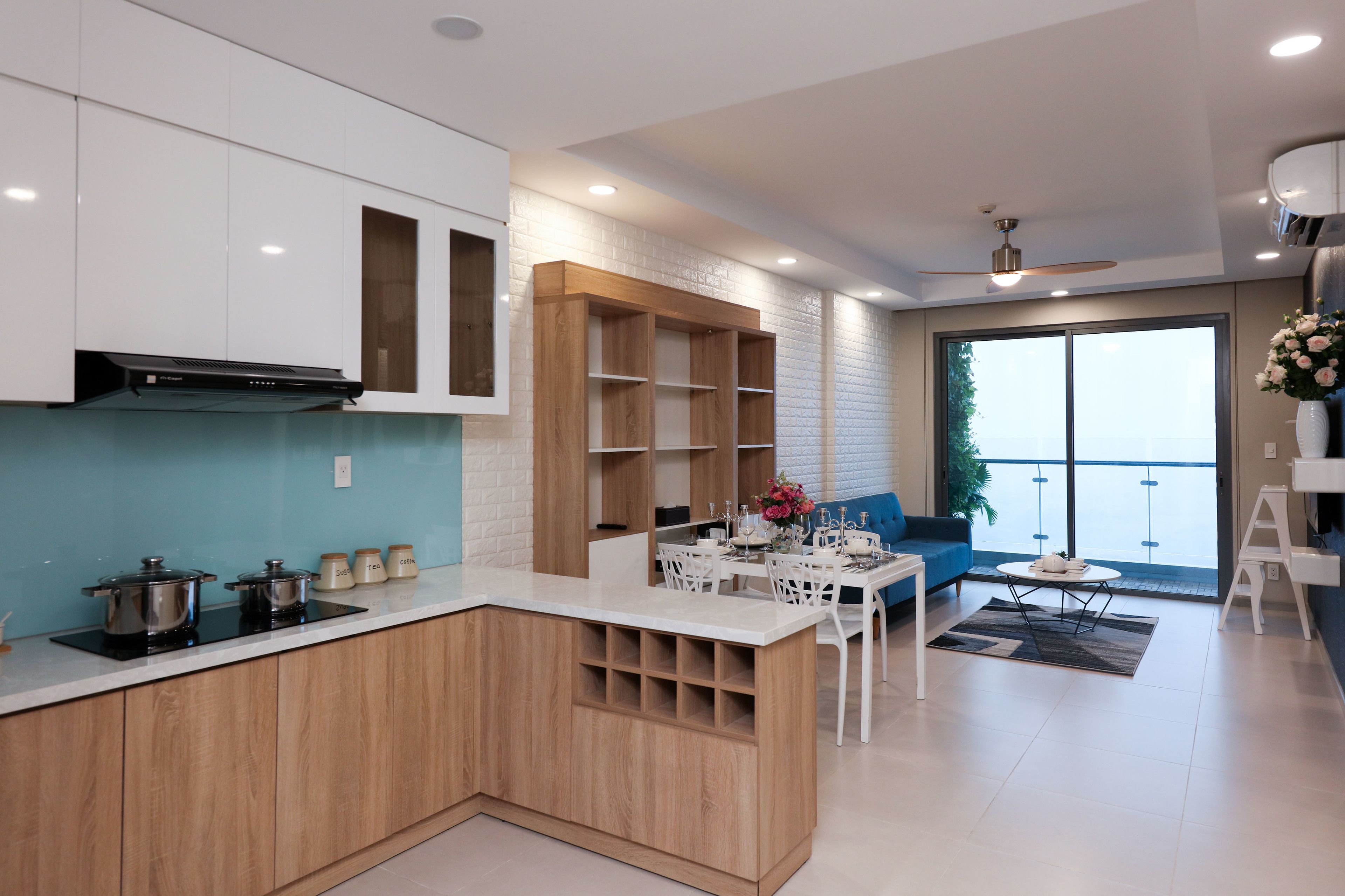 Une cuisine moderne avec des meubles blancs, un îlot central en bois et un coin repas comprenant un canapé bleu et une petite table.