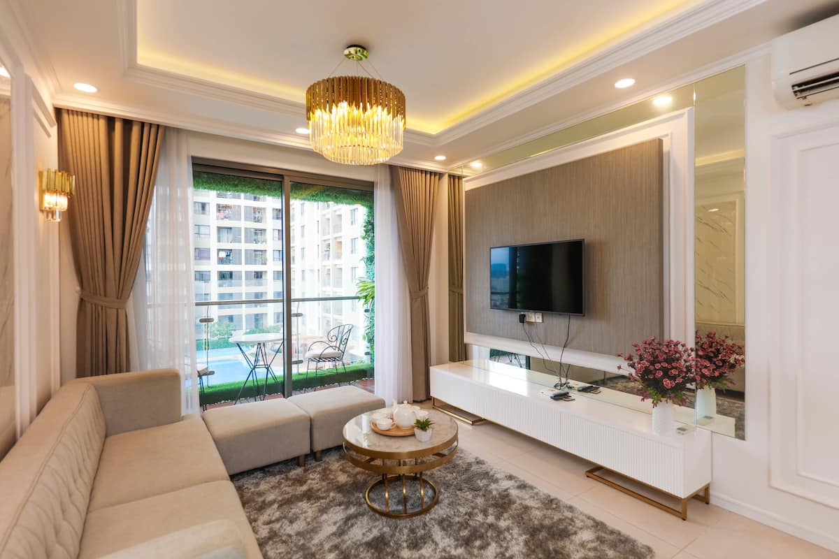 A modern living room with a sofa, a round coffee table, a TV, and a large window with curtains.
