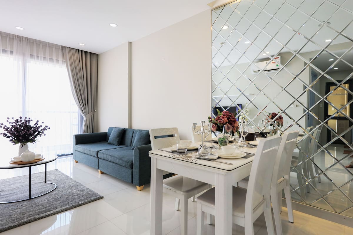 A modern living room with a dining area, a sofa, a coffee table, and a dining table set for a meal.