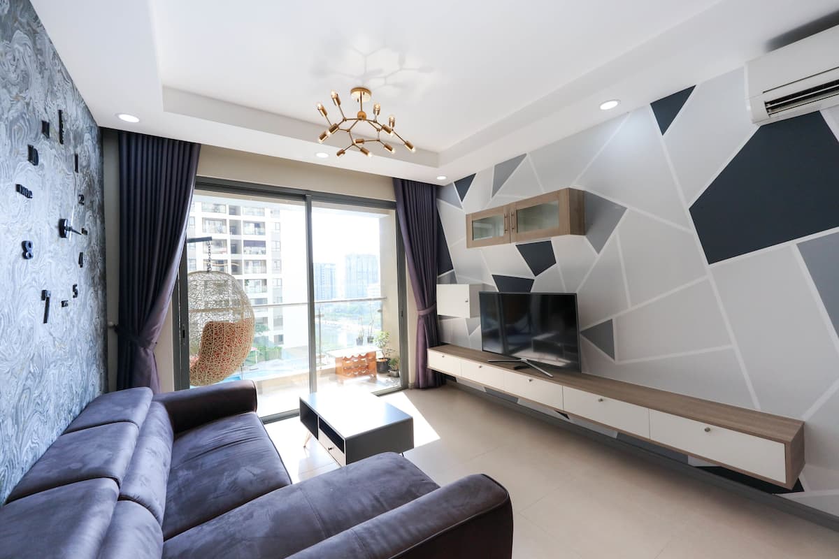 A modern living room with a sofa, TV, and geometric wall design.