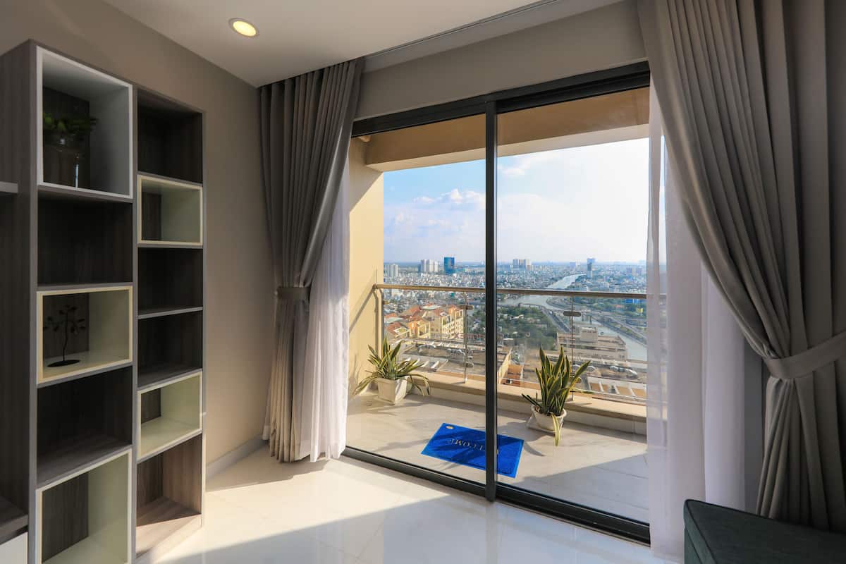 A modern hotel room with a large balcony, a city view, and a built-in bookshelf.