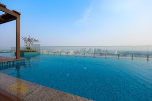 Una piscina a sfioro sul tetto con vista sulla città, una pergola e un piccolo albero.