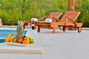 A poolside area with lounge chairs and a fruit platter. - Villa Marina (Vrgorac)
