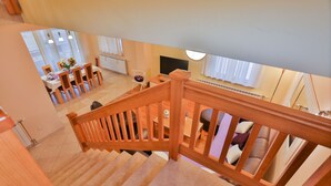 Eine Treppe mit Holzhandläufen führt zu einem Essbereich mit Tisch und Stühlen.