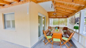 Eine Außenpatio mit einem Holztisch und Stühlen, einem Deckenventilator und Blick auf die Umgebung.