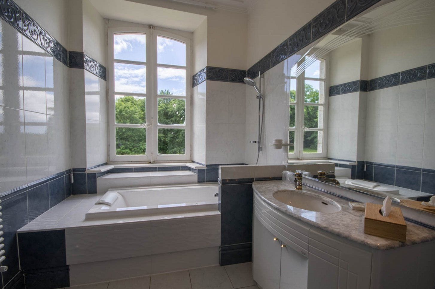 Un baño moderno con bañera, lavamanos y un espejo grande.
