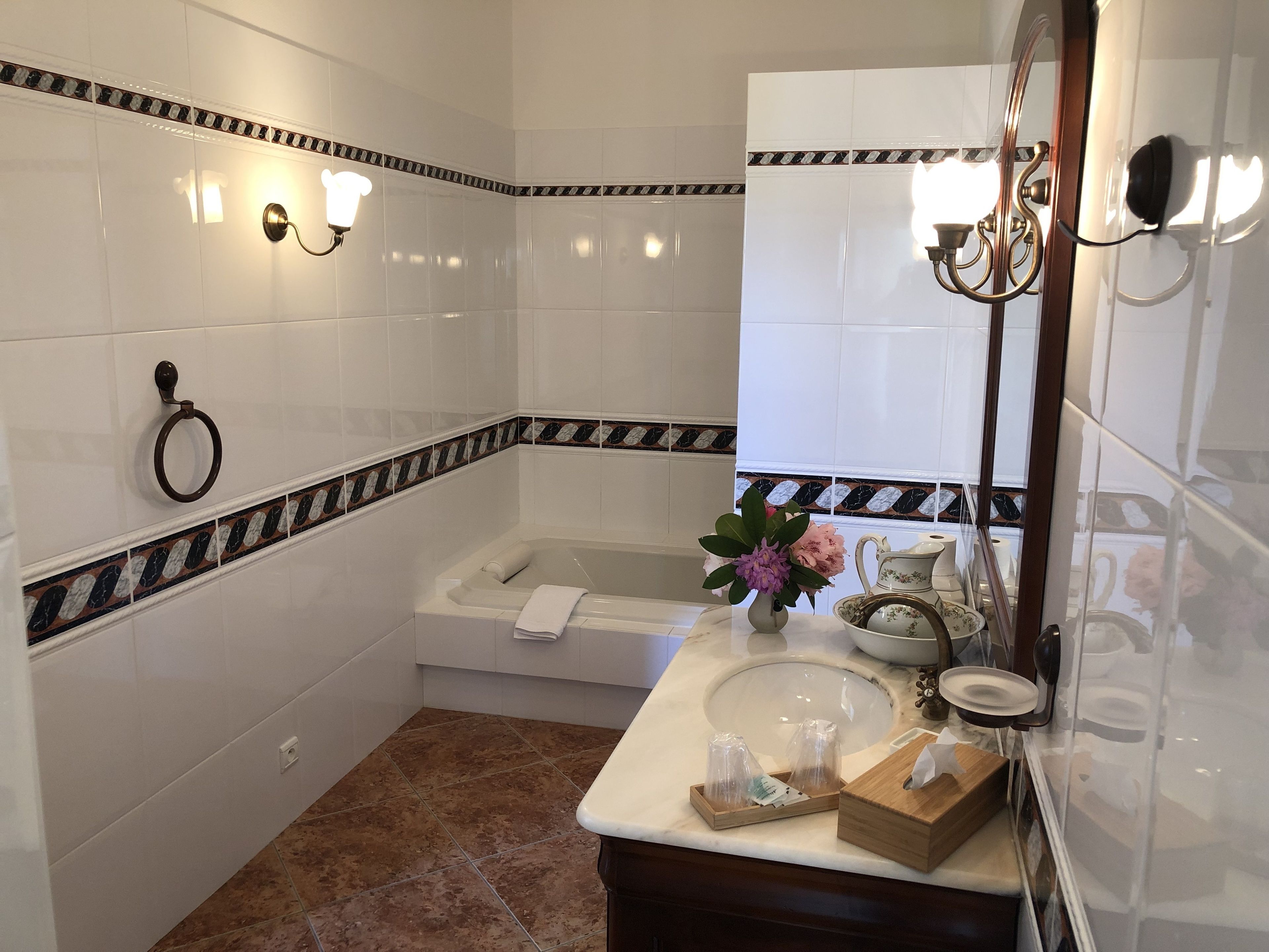A bathroom with white tiles, a bathtub, a sink, and a mirror.