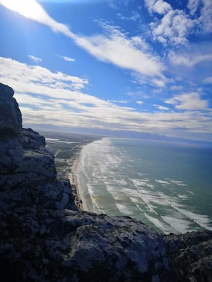 Eine Küstenlandschaft mit einer felsigen Klippe, einem Strand und dem Ozean.