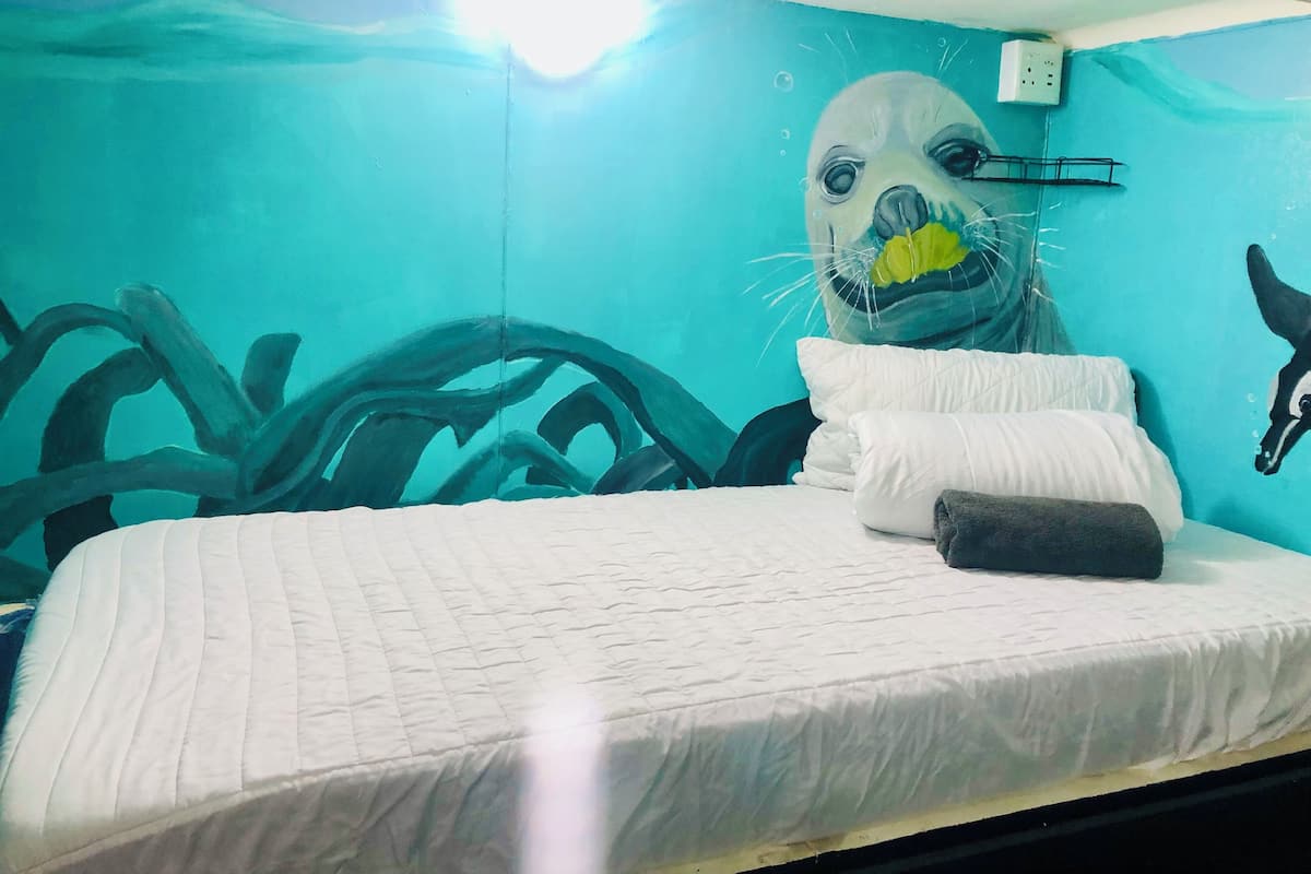 Een kamer met een bed, een muurschildering en een stopcontact.