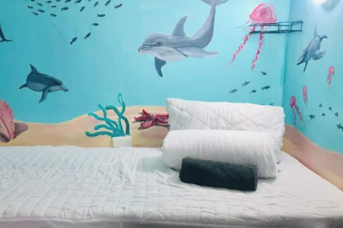 Een slaapkamer met een bed, kussens en een wanddecoratie van zeedieren.