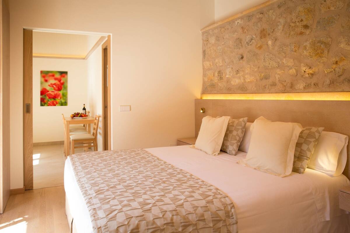 A bedroom with a large bed, a wooden headboard, and a stone wall.
