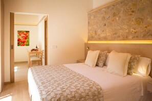A bedroom with a large bed, a wooden headboard, and a stone wall. - Agroturismo S'Arboçar  (Sant Llorenc des Cardassar)