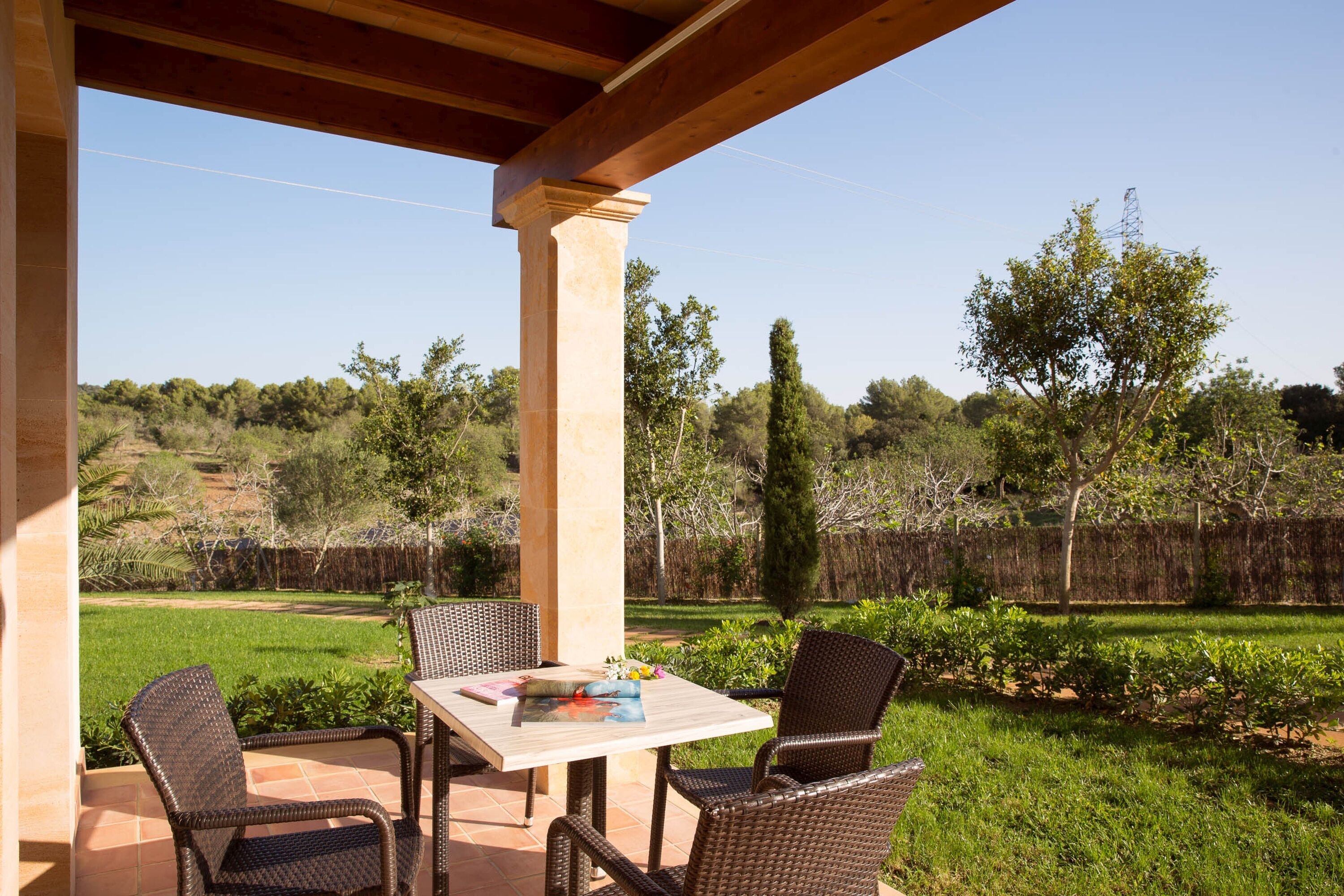 Une terrasse extérieure avec une table et des chaises, entourée d’un jardin et d’une clôture en bois.