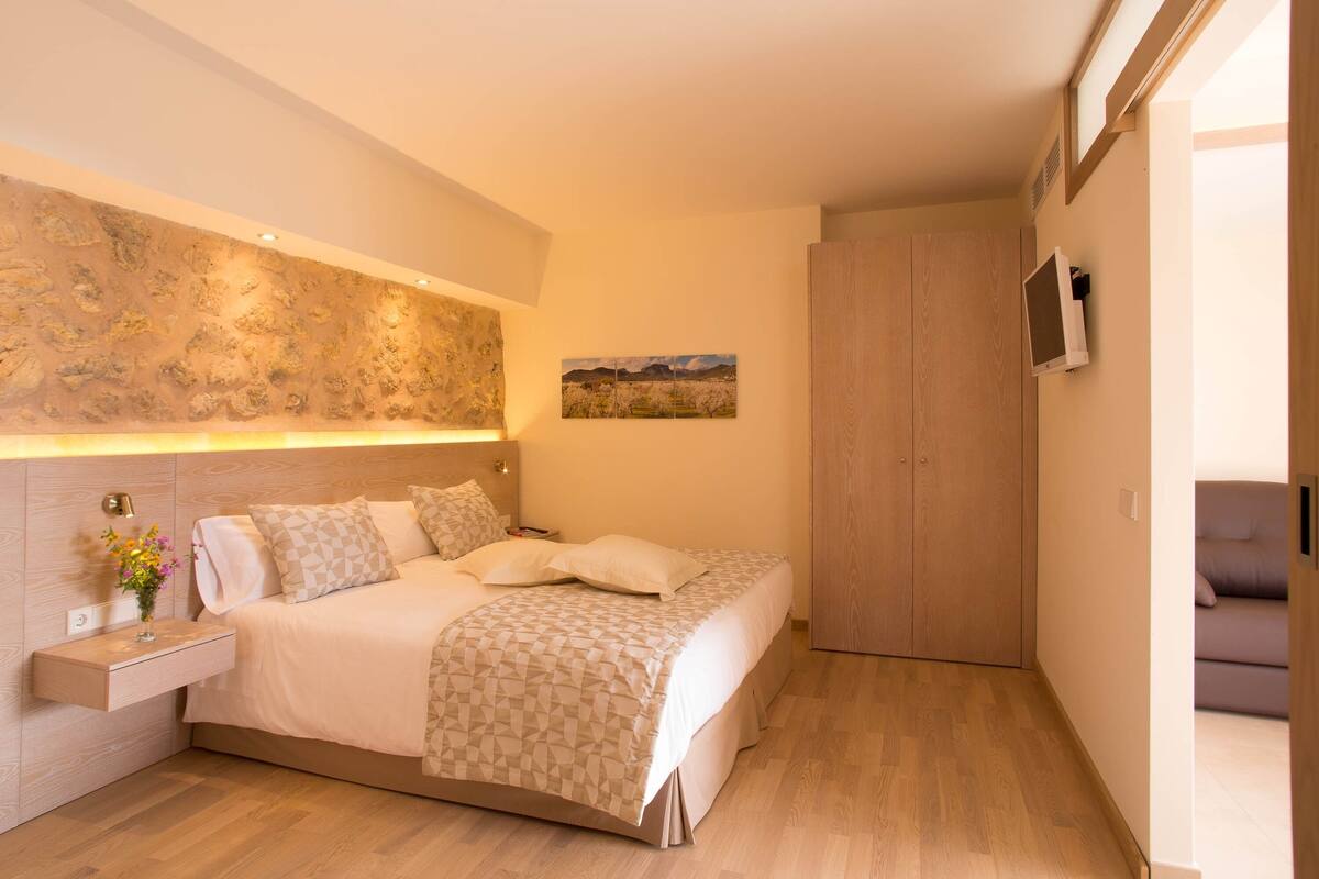 A modern bedroom with a bed, bedside table, and a wall-mounted TV.
