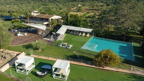 A resort with a swimming pool, outdoor seating, and a view of the surrounding hills.