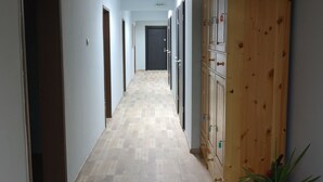 Un pasillo con suelo de madera, un armario de madera y una planta en maceta.