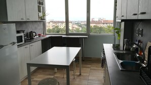Una cocina moderna con armarios blancos, una mesa de comedor y un amplio ventanal con vista a la ciudad.