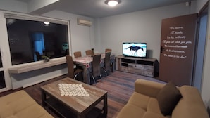 Una sala de estar con televisor, sofá, mesa de centro y un comedor con sillas.