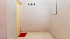 A narrow hallway with a door on the left, a wall-mounted hook, and a red mat on the floor. - Trans Bandara Residence by Zuzu (Deli Serdang)
