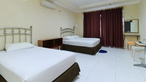 A hotel room with two beds, a desk, a chair, a mirror, and a window with curtains. - Andrin Daspatt Hotel (Makassar)