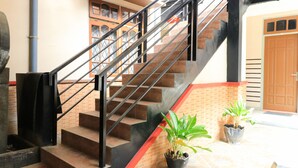 A staircase with metal railings, a red carpet, and potted plants. - Andrin Daspatt Hotel (Makassar)