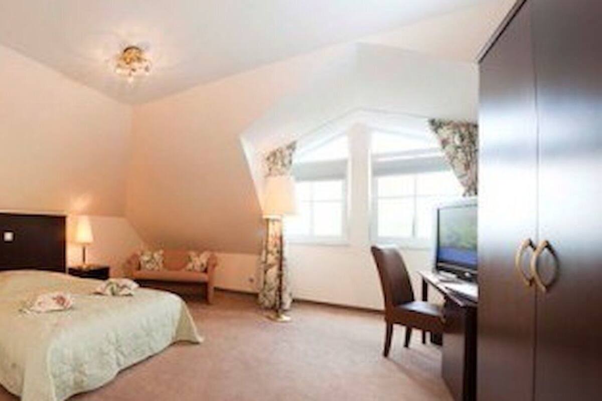 A hotel room with a bed, a desk, a chair, a television, and a window.