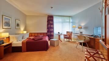 A hotel room with a bed, desk, chair, and a small table.