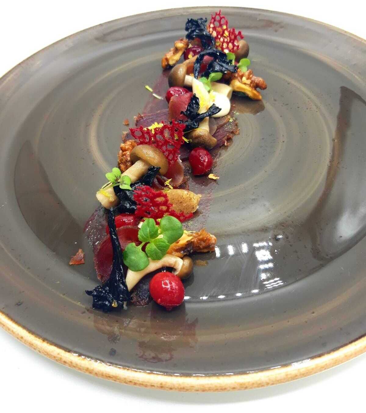 A plate with a variety of food items including mushrooms, berries, and greens.