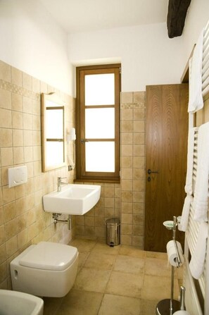 A small bathroom with a toilet, sink, and a wooden door. - Agriturismo Aqua Viva (Acquaviva Picena)