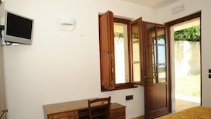 Une pièce comprenant un bureau, une chaise, un lit et un téléviseur fixé au mur.