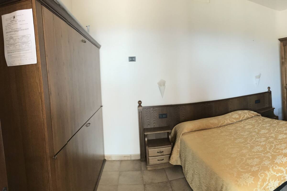 Ein Schlafzimmer mit einem hölzernen Bett, einem Schrank aus Holz und einem kleinen Nachttisch.