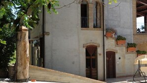 Une cour intérieure avec un bâtiment agrémenté d’une pergola en bois, d’un toit en tuiles et d’un mur en pierre.