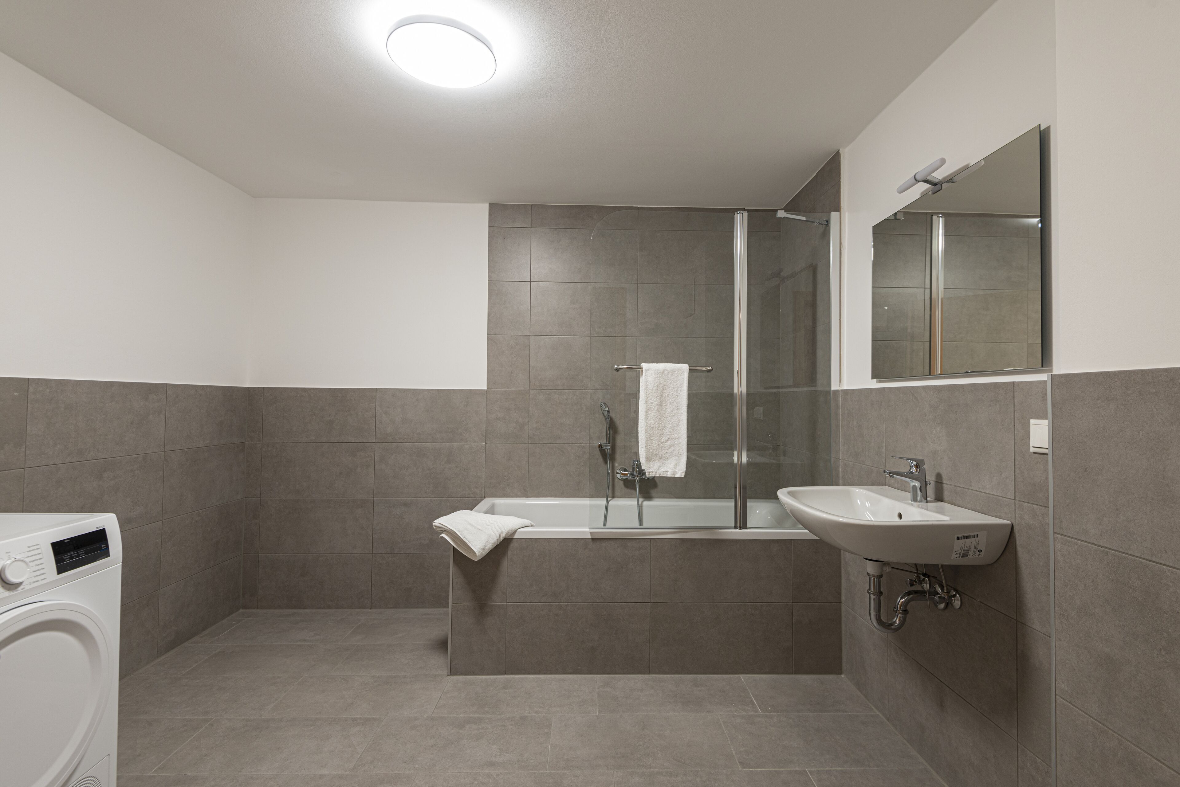 Un baño moderno con lavadora incorporada, bañera y lavabo.