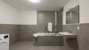 Un baño moderno con lavadora incorporada, bañera y lavabo.