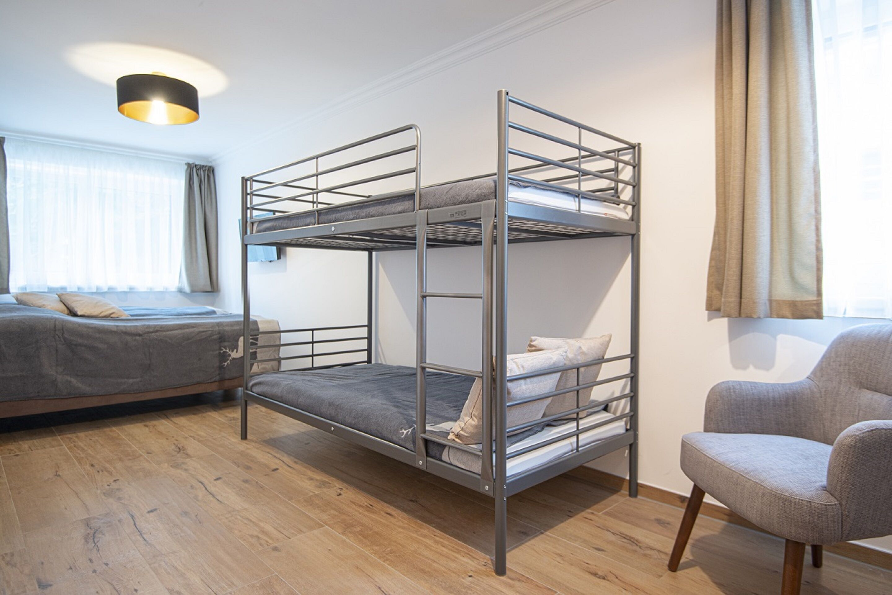 Ein Schlafzimmer mit Etagenbett, Stuhl und einem fenster mit Vorhängen.