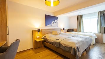 Habitación de hotel con dos camas, suelo de madera, un escritorio y una silla.