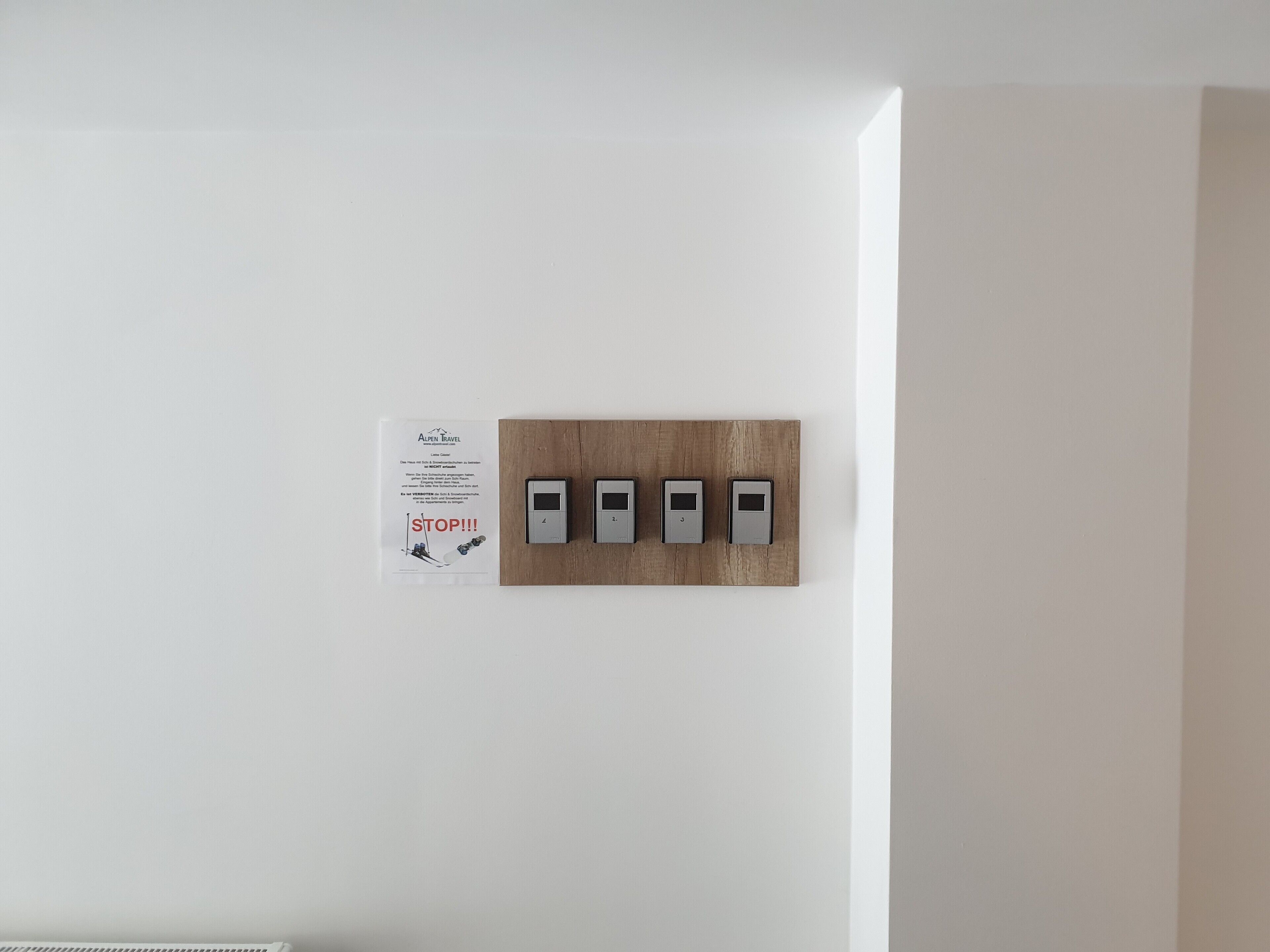 A wall-mounted panel with four switches and a sign with text.