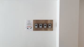 A wall-mounted panel with four switches and a sign with text.