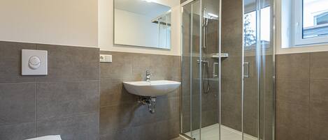 A modern bathroom with a toilet, sink, and glass-enclosed shower.