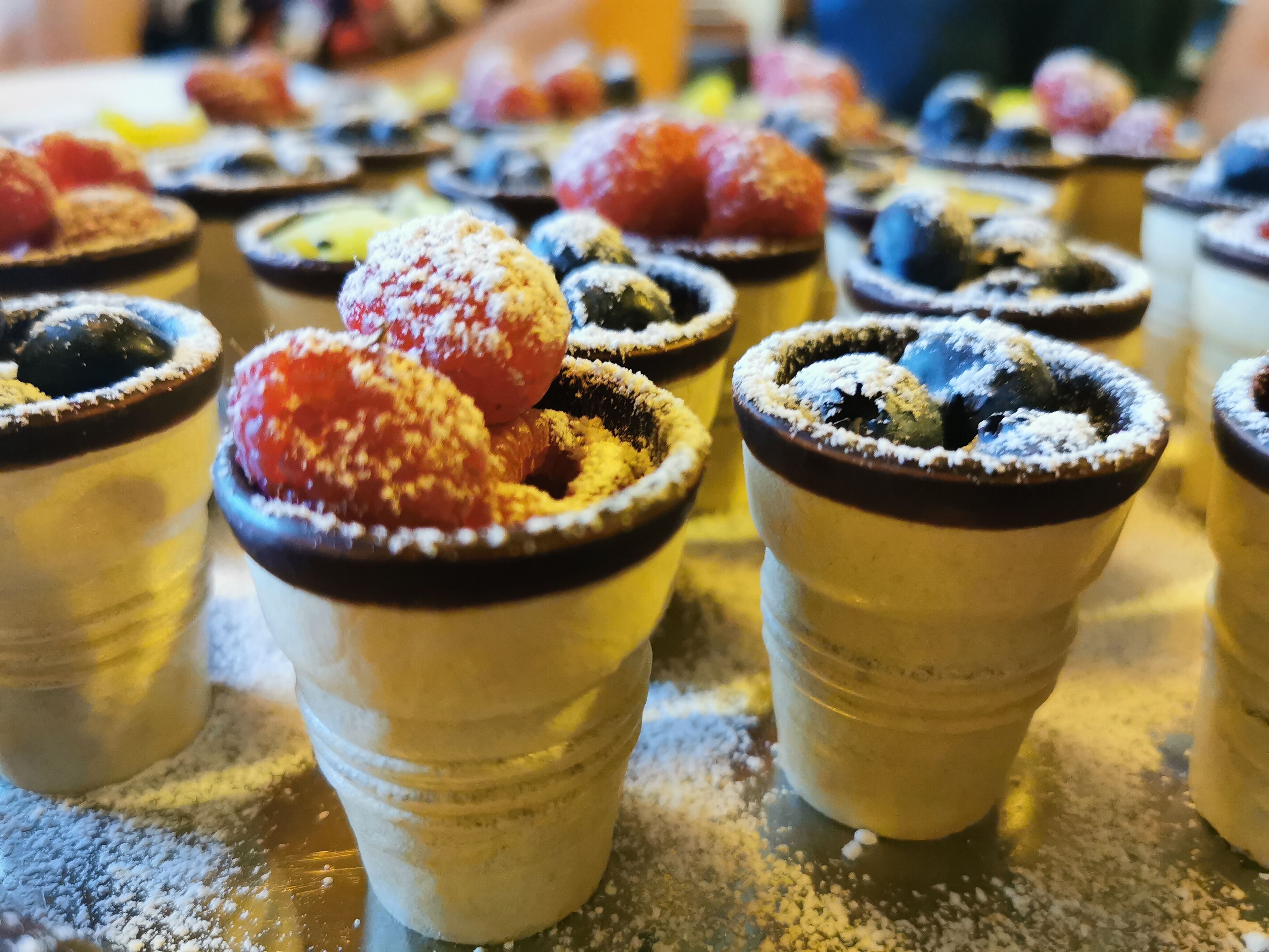 Verschiedene Desserts in kleinen Gläsern, manche bestäubt mit Puderzucker.