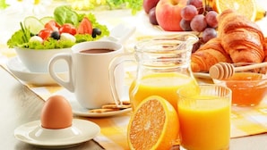 En frukostuppläggning med en sallad, croissanter, apelsinjuice och kaffe.